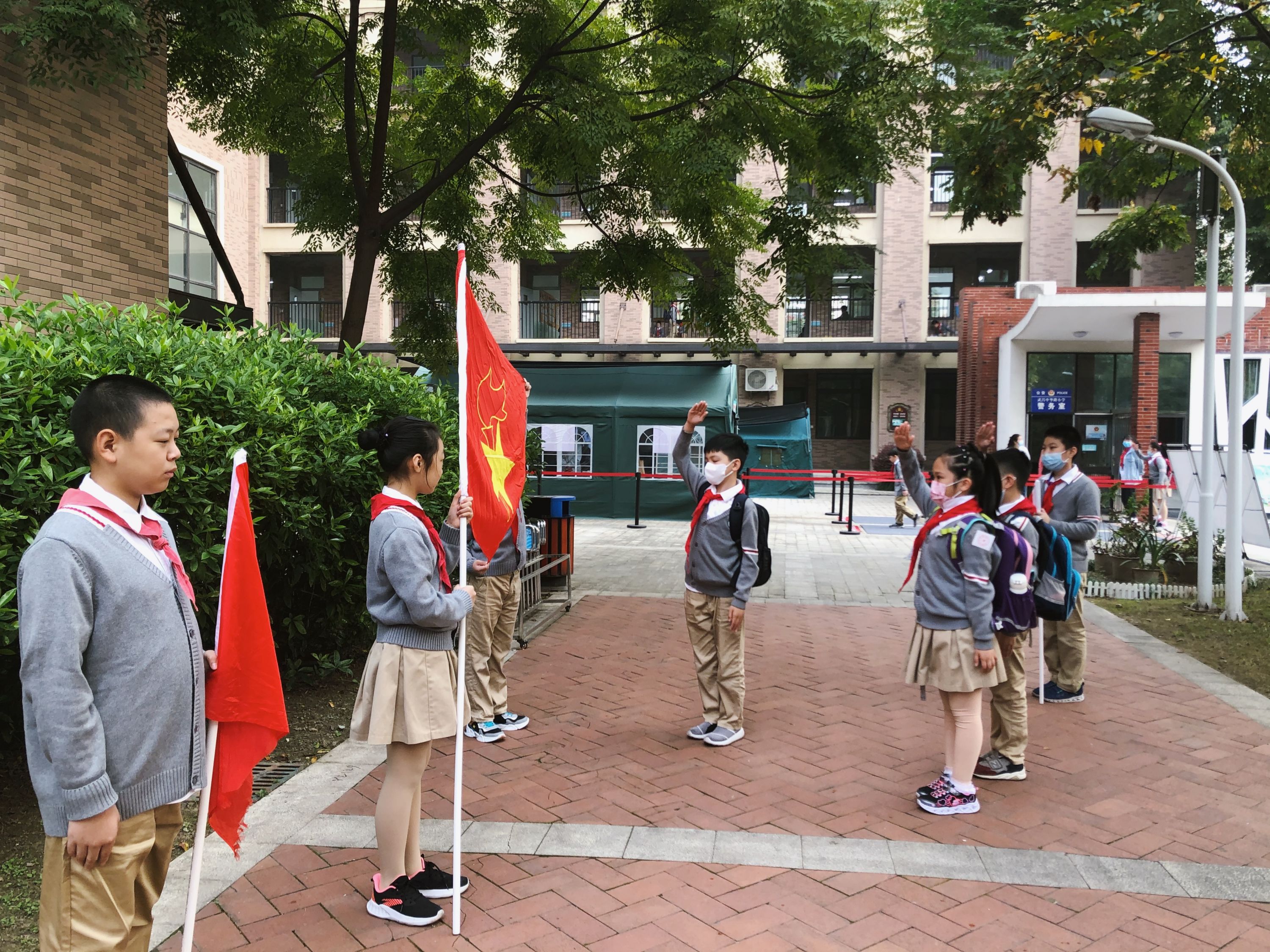 在中华路小学橡树湾校区,面对迎风飘扬的队旗,队员们一个个驻足敬礼